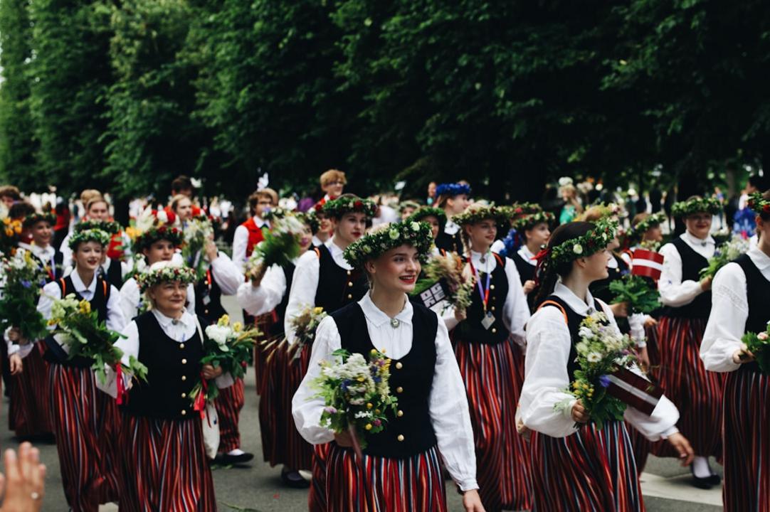 Dress code for Latvia | Which clothes to bring 4 Latvians in traditional folk dress at a summer festival procession, Riga